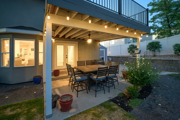 Covered patio area with concrete surfacing, string lighting, and direct access through double glass doors
