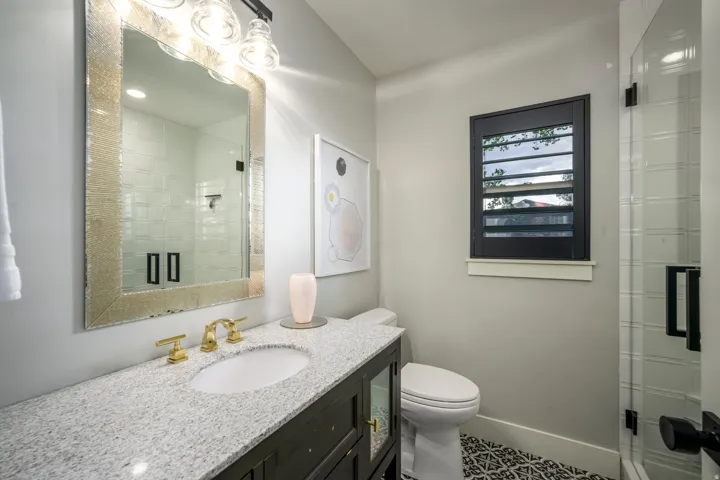 Vanity with a light-colored countertop, undermount sink, and brass-finish faucet
