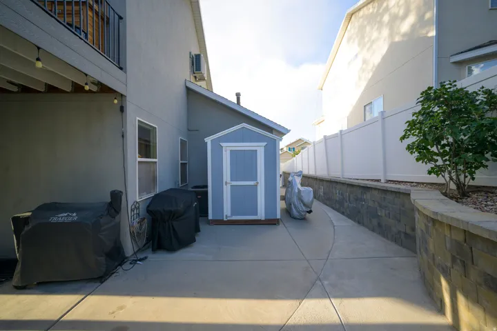 Patio with concrete surfacing, a retaining wall with stone-look blocks, and a privacy fence