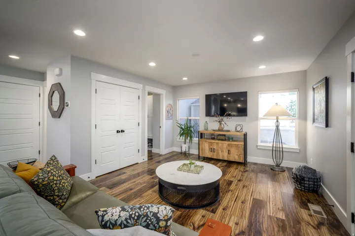Recessed lighting illuminates the wood-finish flooring and light grey walls