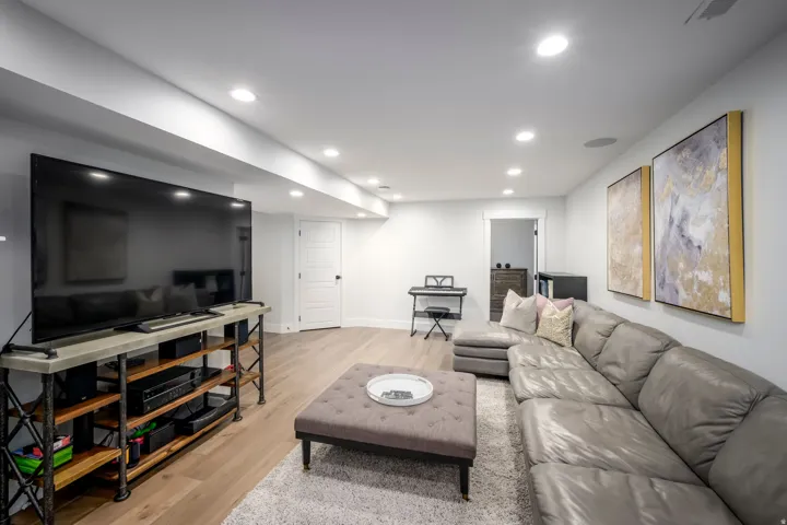Recessed lighting illuminates this expansive room featuring light wood-finish flooring