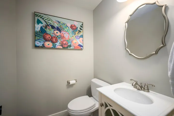 White vanity with decorative cabinet doors, integrated sink, brushed nickel faucet, and a decorative framed mirror