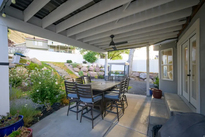 Covered concrete patio with exposed beam ceiling and ceiling fan