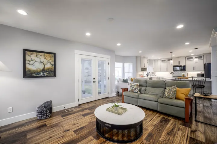 Recessed lighting, wood-finish flooring, white trim, double French doors, and a kitchen featuring light cabinetry and pendant lighting