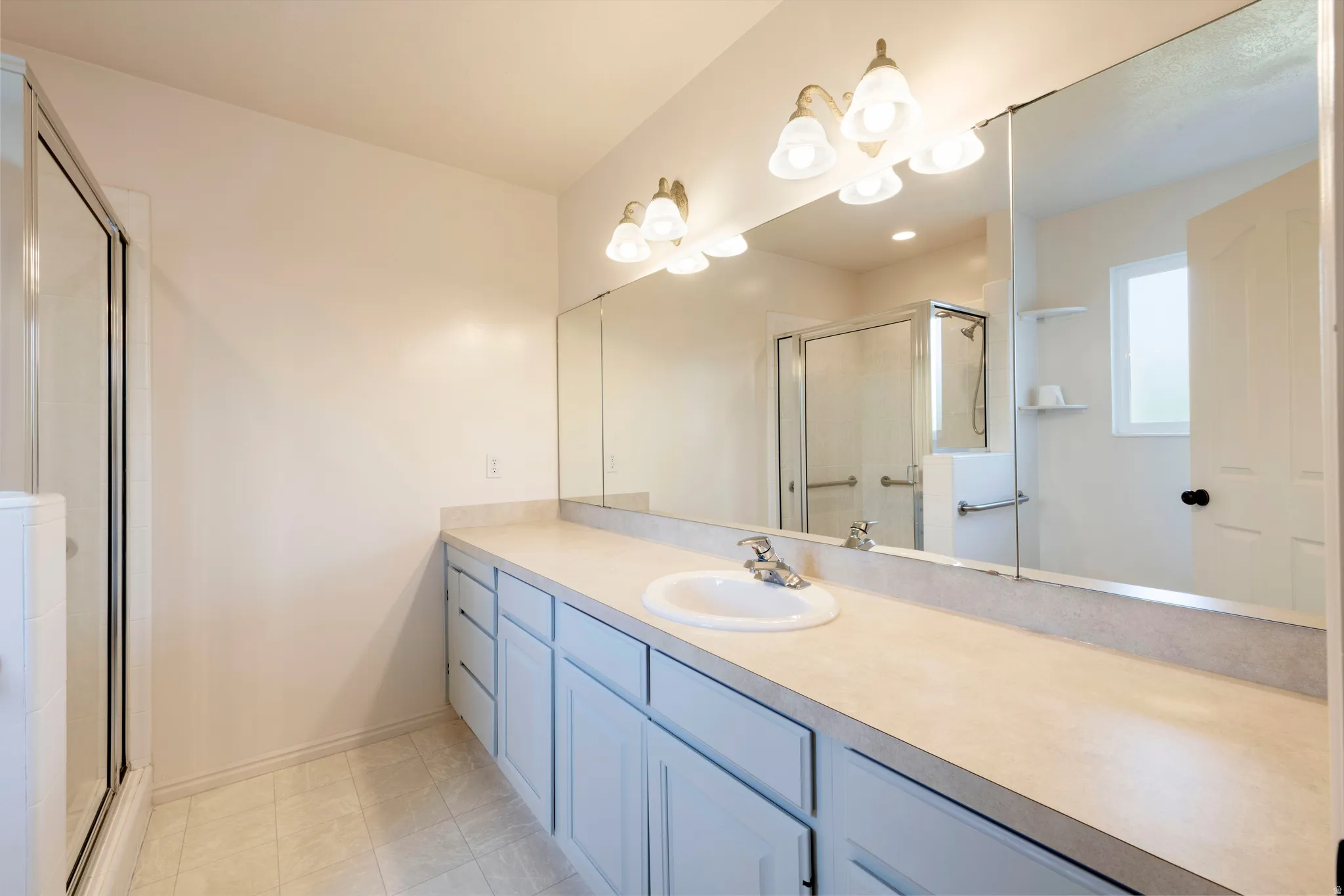 Double vanity with an integrated basin sink, light-colored countertop, and a large wall-mounted mirror