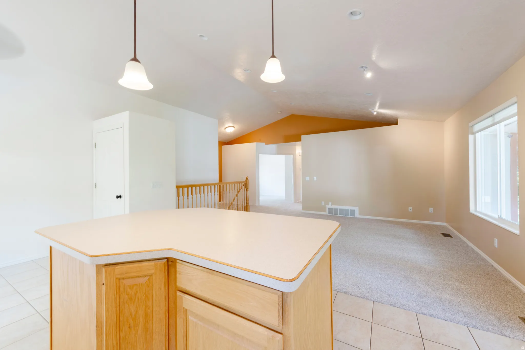 Kitchen island with light wood-finish cabinetry and solid surface countertop