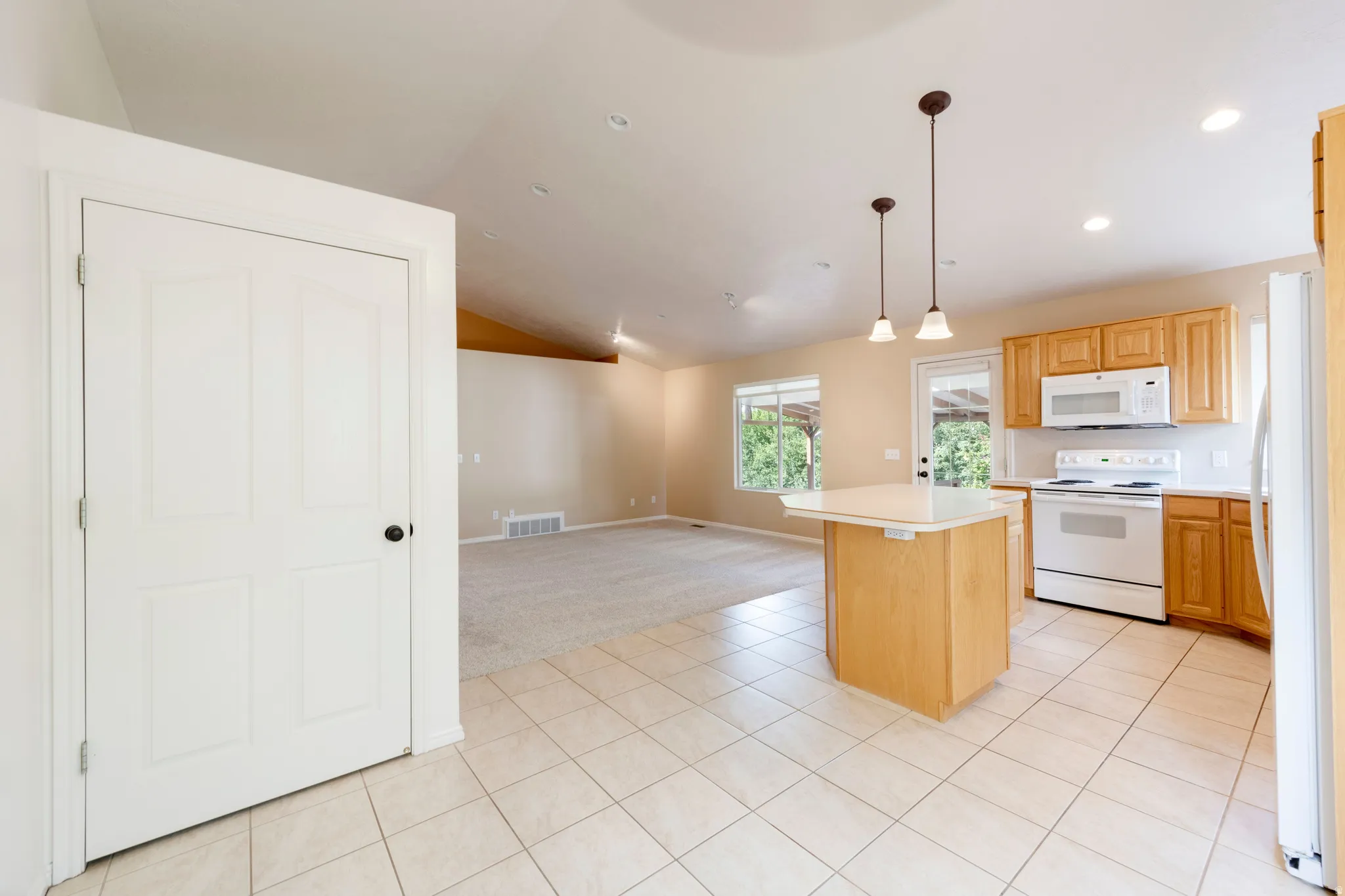 Kitchen featuring tile flooring, wood cabinetry, an eat-at island, and recessed lighting