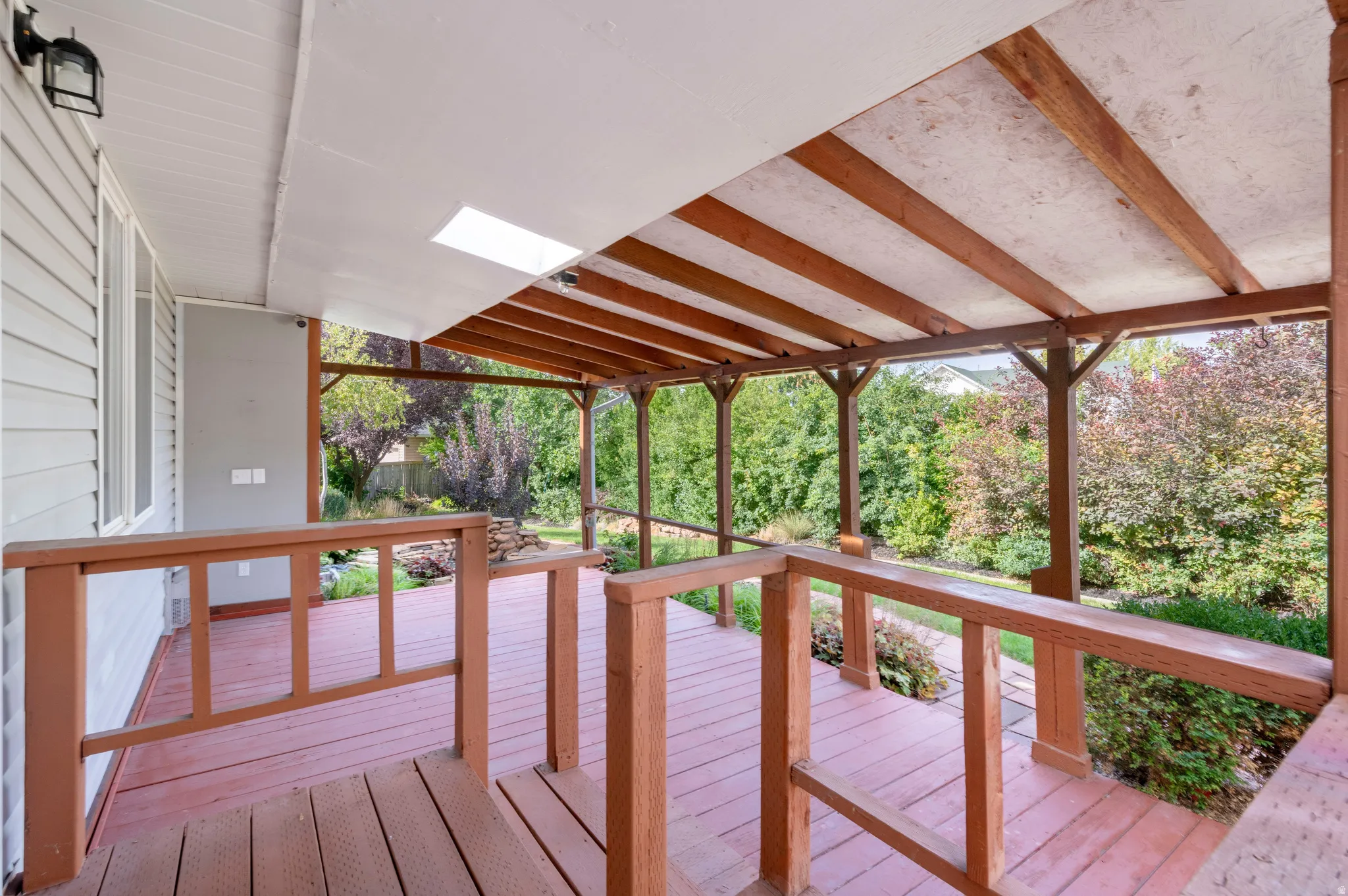 Expansive covered deck featuring a wood-tone railing and support beams