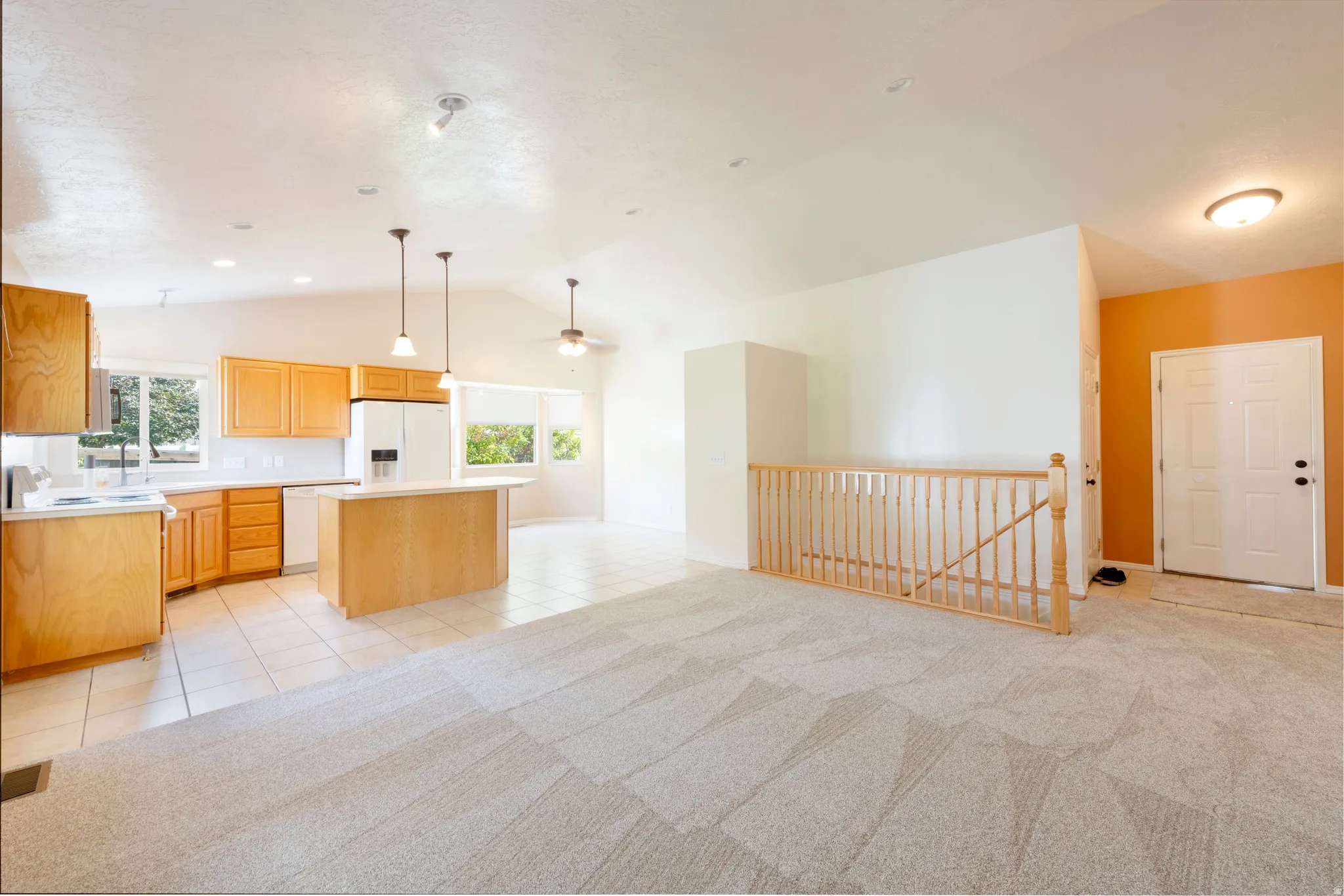 Vaulted ceilings, a kitchen island, and hardwood cabinetry define this bright space