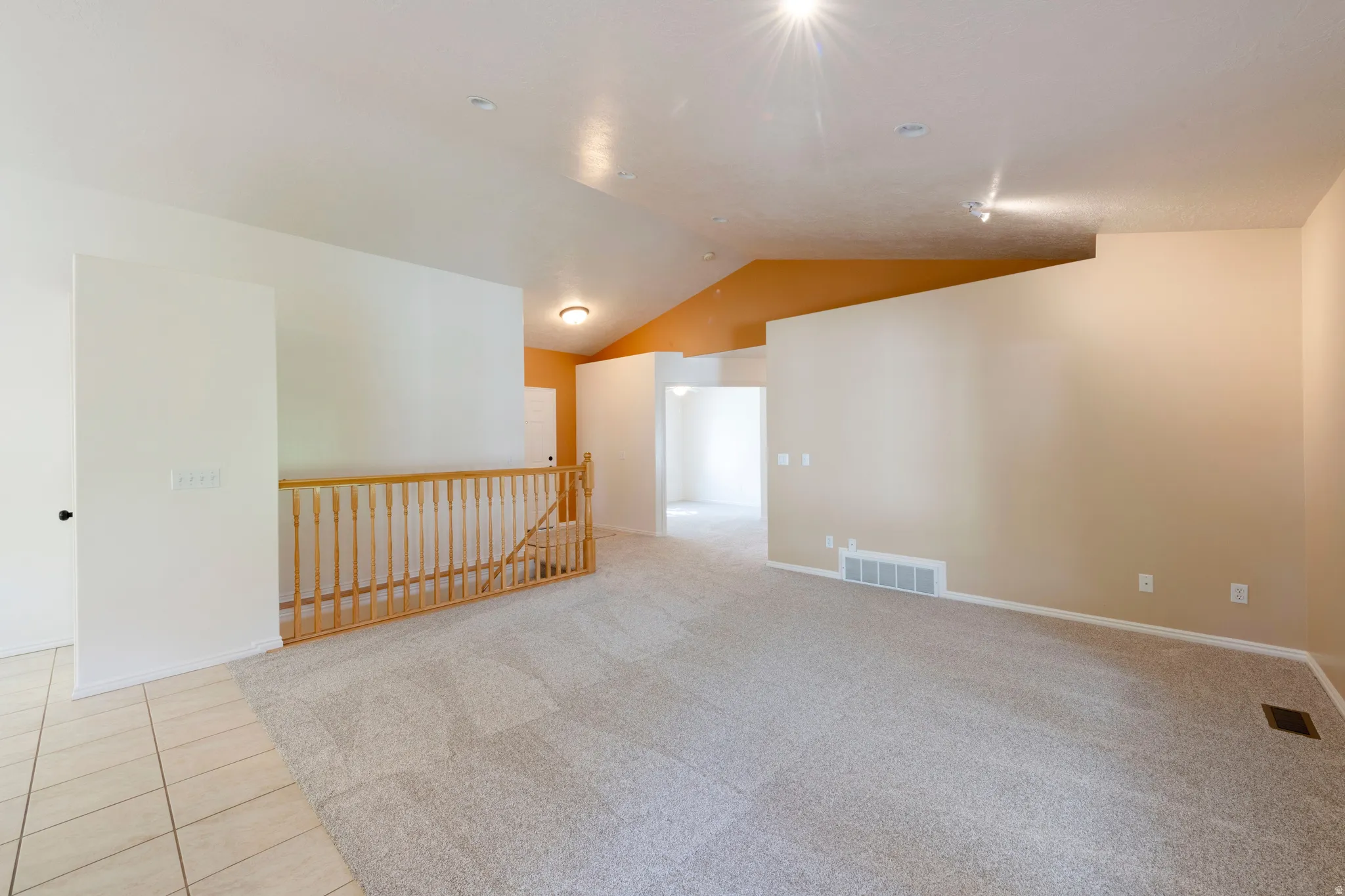 Vaulted ceilings, track lighting, recessed lighting, neutral wall tones, and carpet flooring
