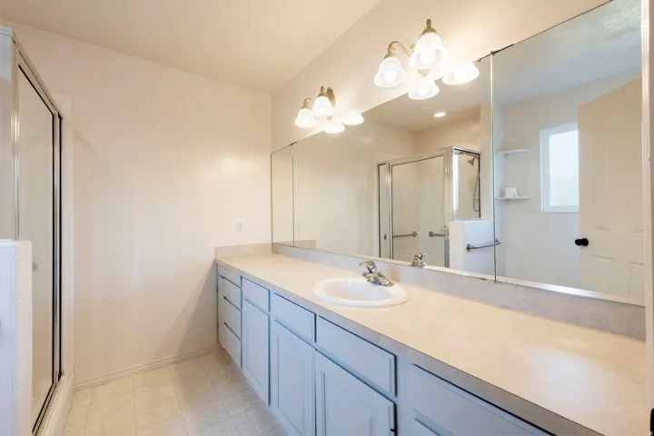 Double vanity with an integrated basin sink, light-colored countertop, and a large wall-mounted mirror