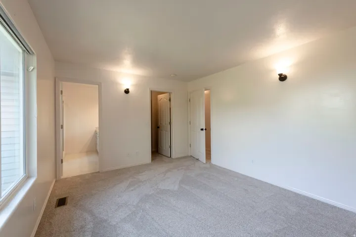 Expansive room with neutral carpeting, white walls, and a large window