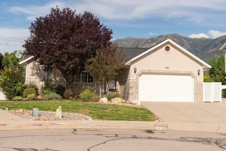 Front exterior with an attached two-car garage, stucco siding, and a brick veneer accent