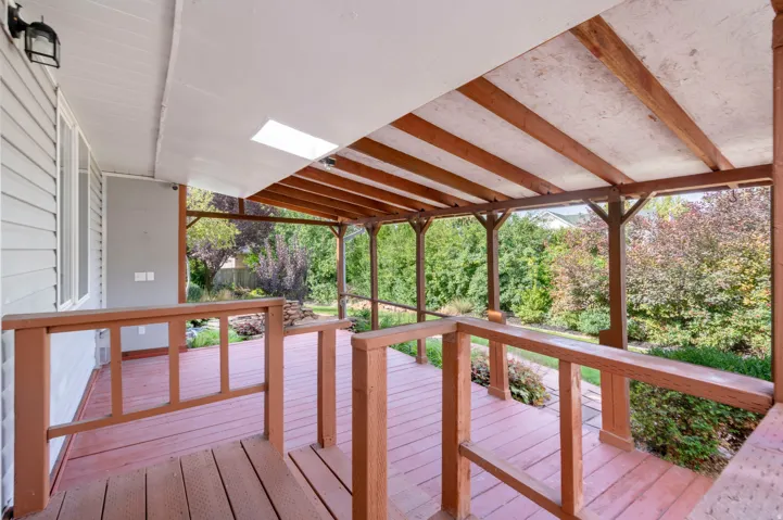 Expansive covered deck featuring a wood-tone railing and support beams