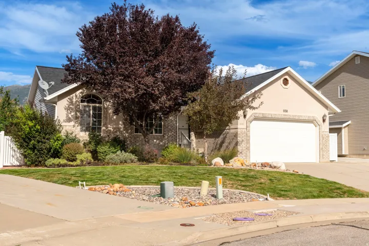 Stucco and brick facade with an attached two-car garage, mature landscaping, and a manicured lawn