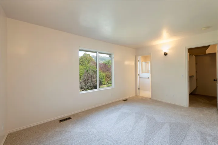 Neutral wall paint, light gray carpet flooring, and a large window with white trim
