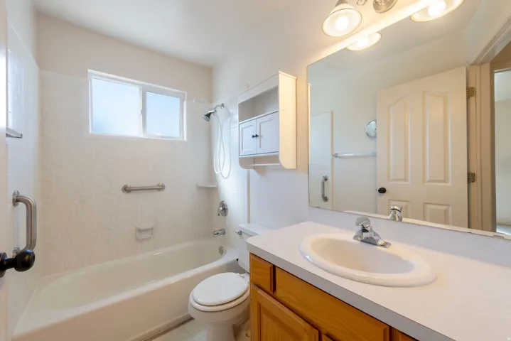 Built-in vanity with a single basin sink, wall-mounted mirror, and overhead light fixture