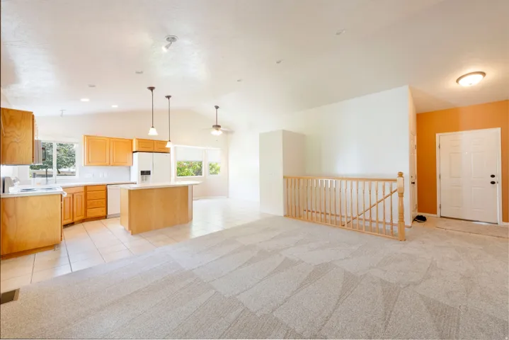 Vaulted ceilings, a kitchen island, and hardwood cabinetry define this bright space