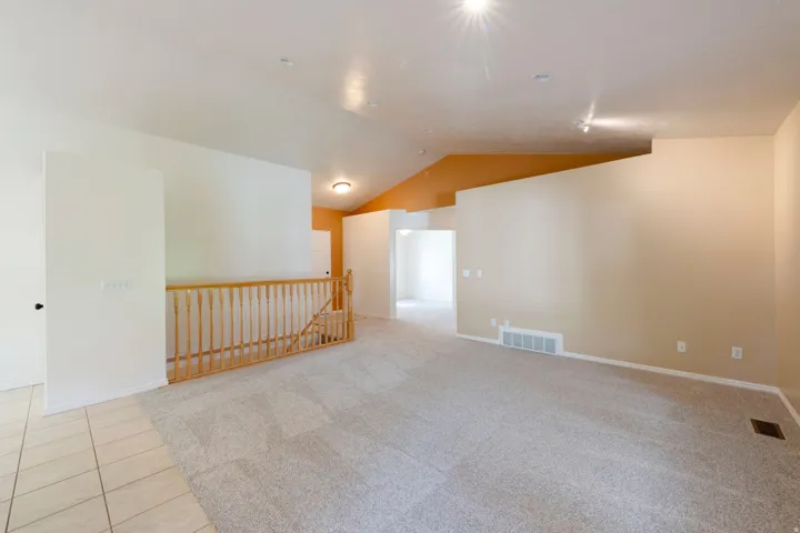 Vaulted ceilings, track lighting, recessed lighting, neutral wall tones, and carpet flooring