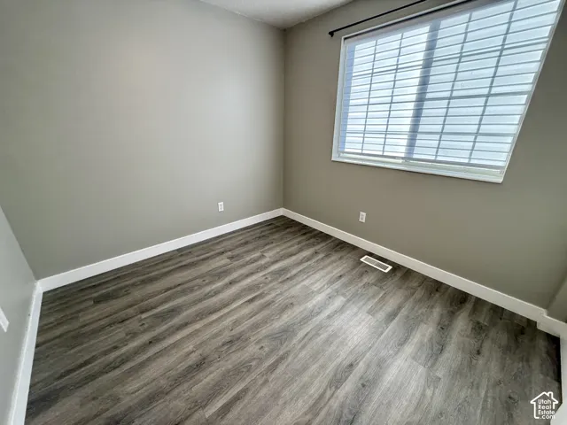Neutral wall paint, wood-finish flooring, white trim, and a window with blinds