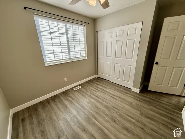 Wood-finish flooring, white window blinds, and white panel doors