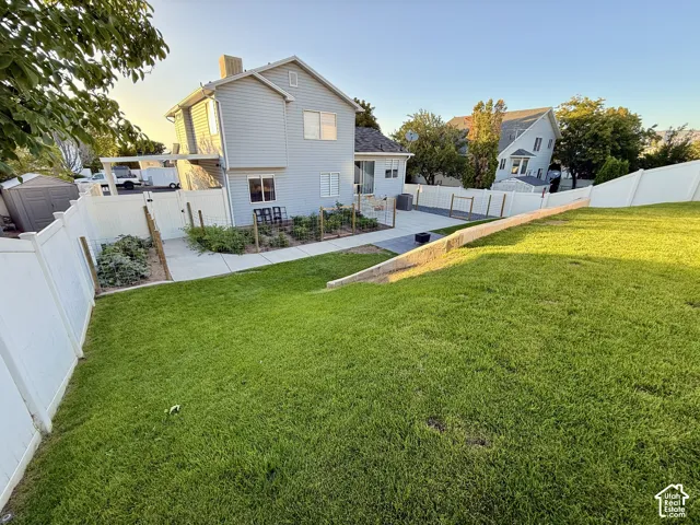 Expansive lawn with a retaining wall, concrete patio, and garden beds