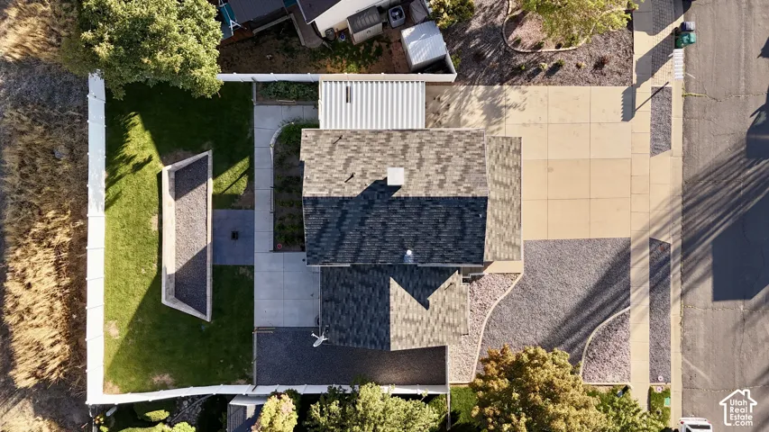 Asphalt shingle roofing, concrete driveway, gravel landscaping, and a manicured lawn