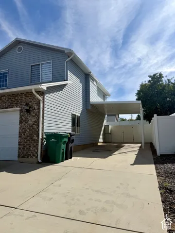 Attached carport with a concrete driveway and vinyl fencing