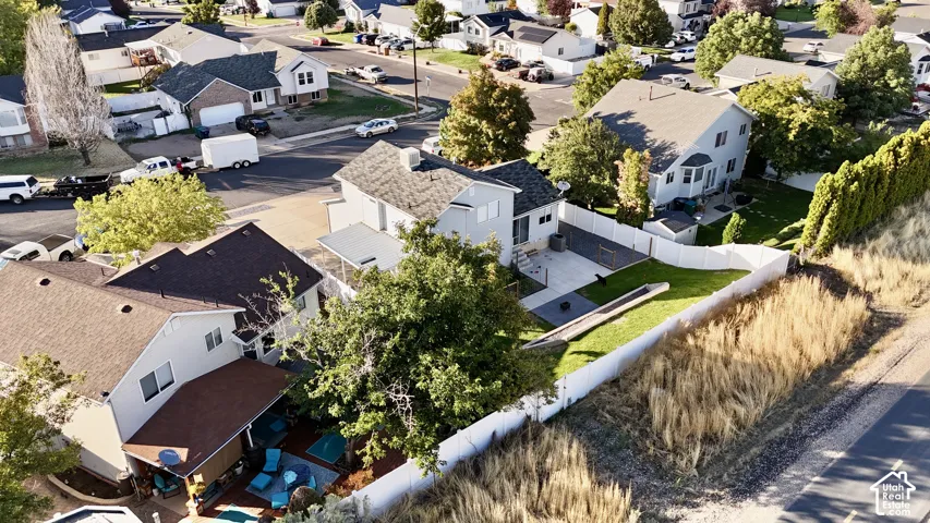 Expansive backyard featuring a manicured lawn, white privacy fencing, and a paved patio area