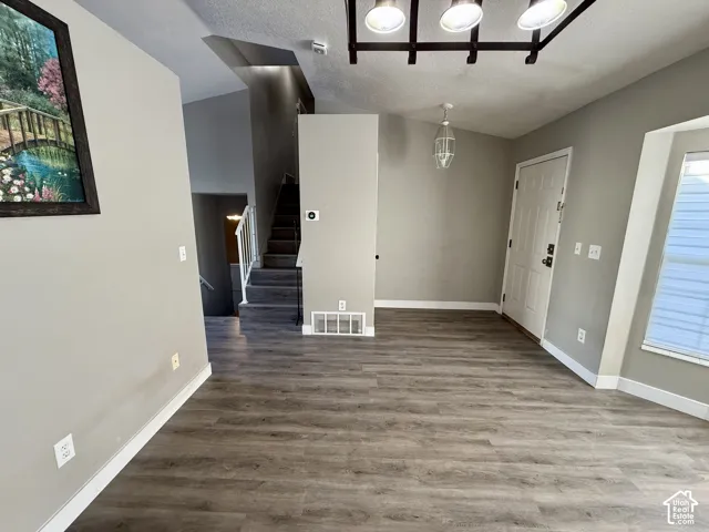 Wood-finish flooring throughout, neutral painted walls, white trim, and a contemporary ceiling light fixture