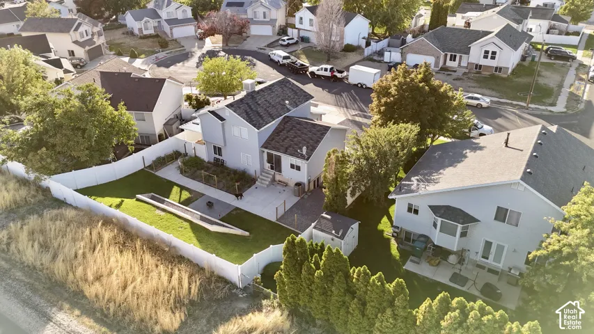 Expansive backyard featuring a manicured lawn, concrete patio, white privacy fencing, and a built-in storage shed