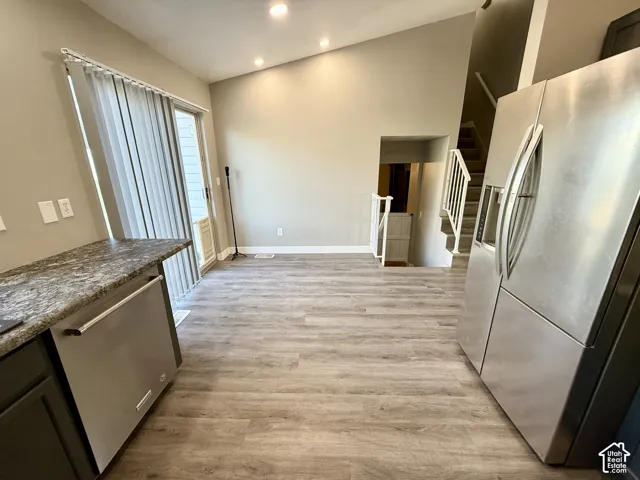 Vaulted ceiling, recessed lighting, wood-finish flooring, stainless steel dishwasher, and a sliding glass door