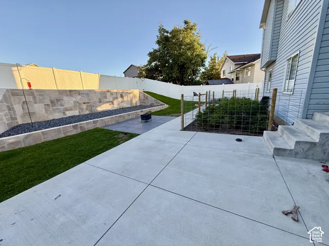 Expansive concrete patio with a tiered stone retaining wall and integrated garden space
