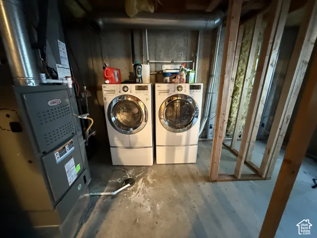 Full-size washer and dryer, utility sink, exposed ceiling ductwork, concrete flooring, and unfinished framed wall