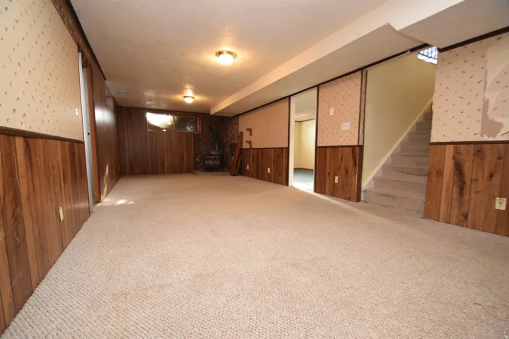 Expansive carpeted area with wood paneling and recessed lighting