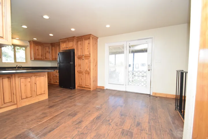 Kitchen featuring wood-finish flooring, recessed lighting, wood cabinetry, and a black refrigerator