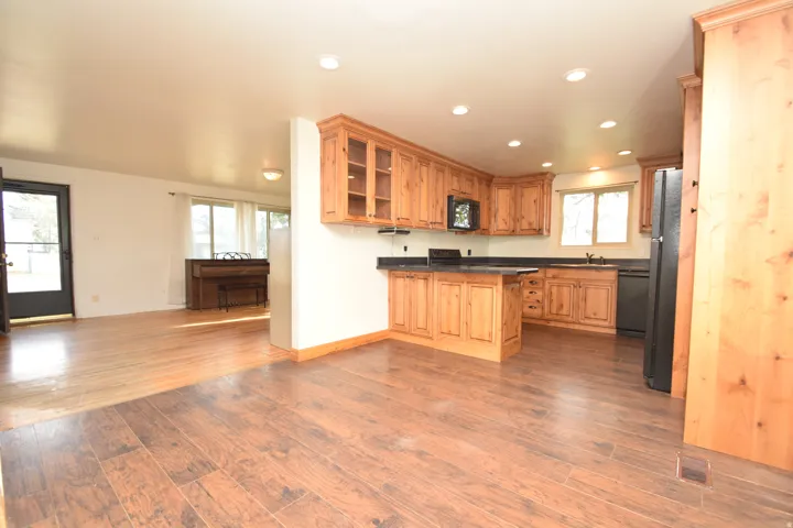 Kitchen with wood-finish cabinetry, dark countertops, and recessed lighting
