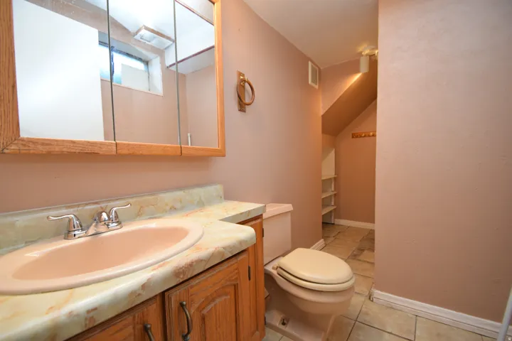 Built-in wood vanity with laminate countertop, chrome faucet, and integrated sink