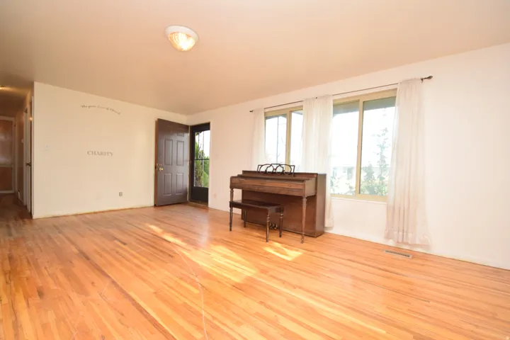 Hardwood flooring, multiple windows providing natural illumination, ceiling-mounted light fixture, and a solid-panel entry door