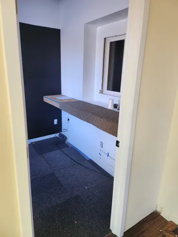 Built-in desk surface with window, paneled accent wall, and modular carpet flooring