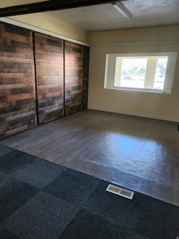 Wood-finish sliding closet doors, a recessed window, and mixed flooring with wood-finish and carpeted sections
