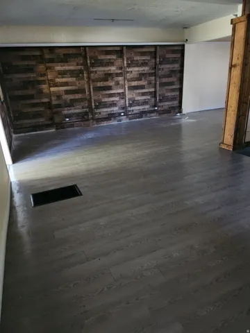 Wood-finish flooring throughout, featuring a natural wood accent wall with recessed lighting and a wood-wrapped structural beam
