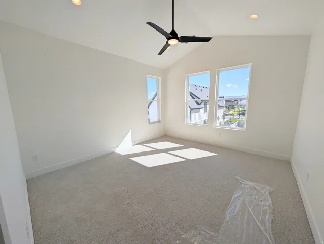 Primary bedroom with Vaulted ceiling with a contemporary ceiling fan, recessed lighting, and three tall windows