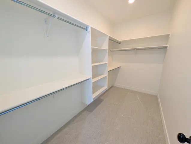 Walk-in closet featuring built-in shelving, multiple hanging rods, and recessed lighting