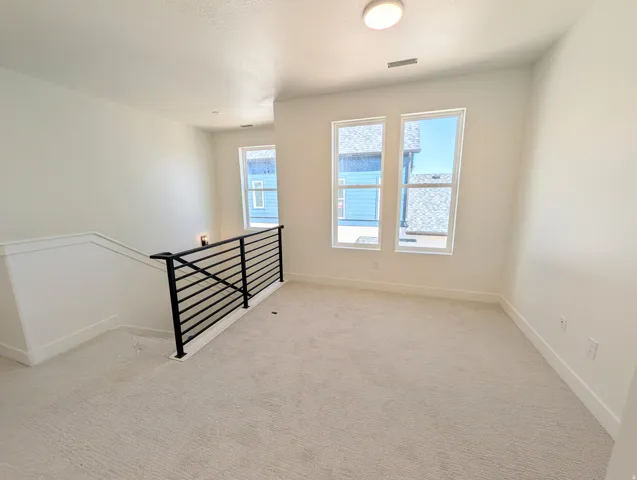 Carpeted loft area with white walls and a contemporary black metal stair railing