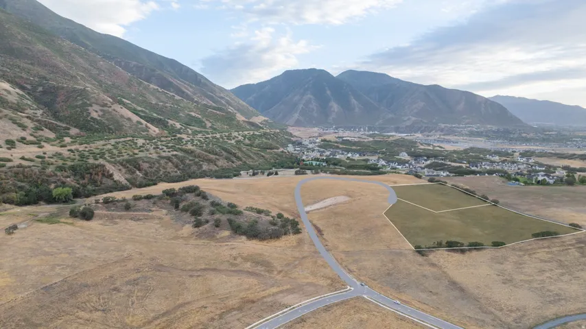 Expansive land parcel featuring a maintained green area, undeveloped natural terrain, and distant mountain ranges