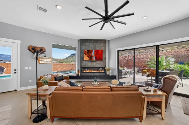 Corner fireplace with a stone-finish facade, wide sliding glass doors, recessed lighting, and a modern ceiling fan