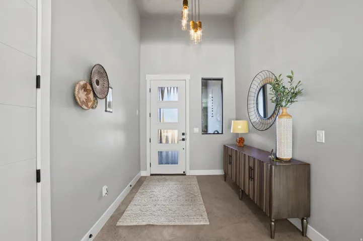 Entryway featuring a white front door with multiple glass panes, a tall ceiling, and a modern light fixture