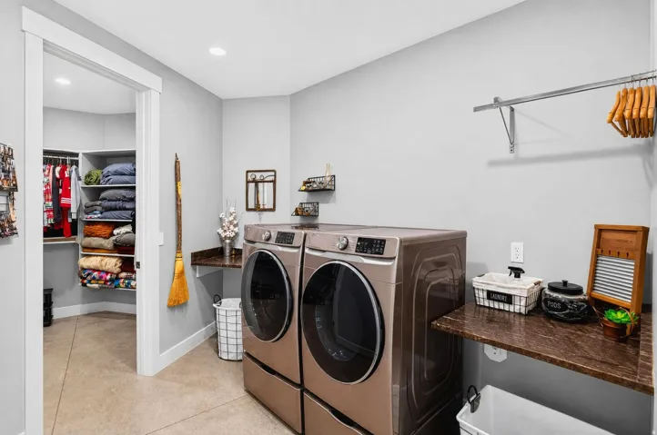 Laundry area featuring a built-in hanging rod, recessed lighting, stone-finish countertops, and an adjacent walk-in closet with built-in shelving
