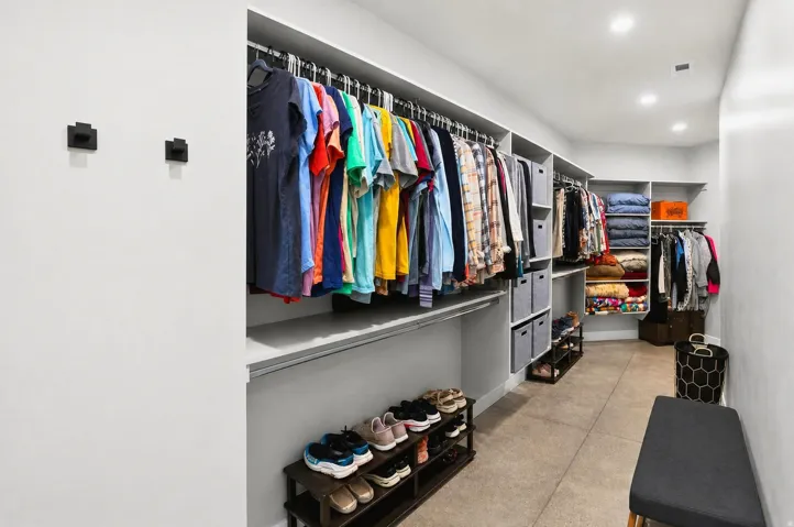 Walk-in closet featuring built-in shelving, multiple hanging rods, and recessed lighting